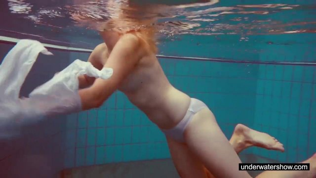 Рыжая шлюшка раздевается в бассейне и светит натуральной грудью
